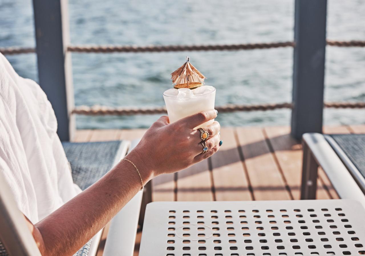 A woman holding a drink by the pool.