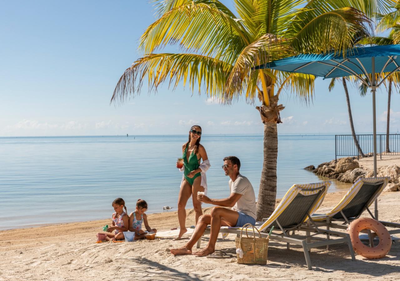 A family sitting at the beach at Three Waters Resort in Islamorada, Florida.