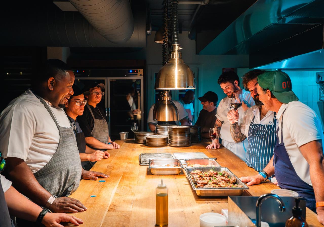A group of chefs all stand around the kitchen at Kindler for Helm to Hearth at Three Waters Resort & Marina.