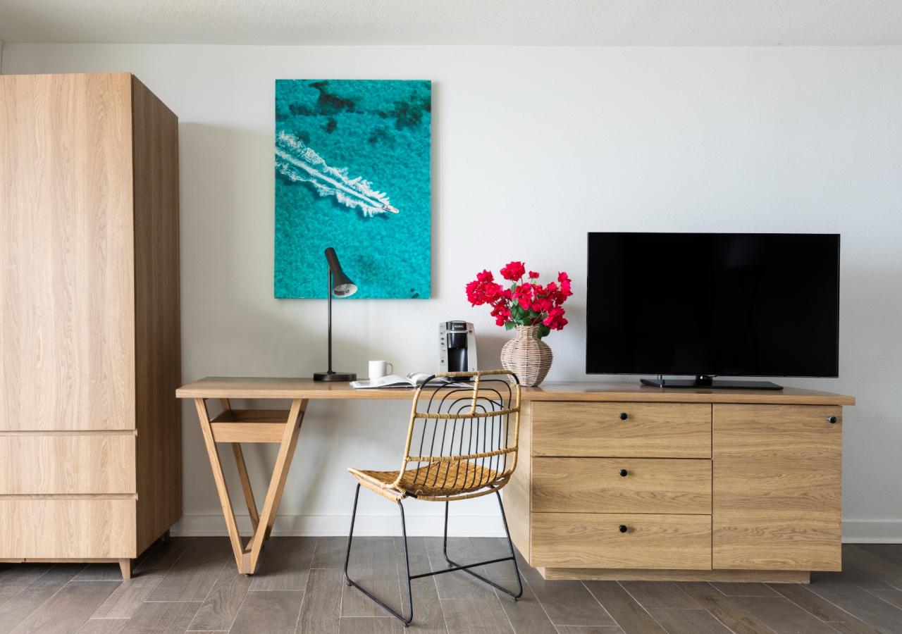 A view of a desk with a TV and dresser.