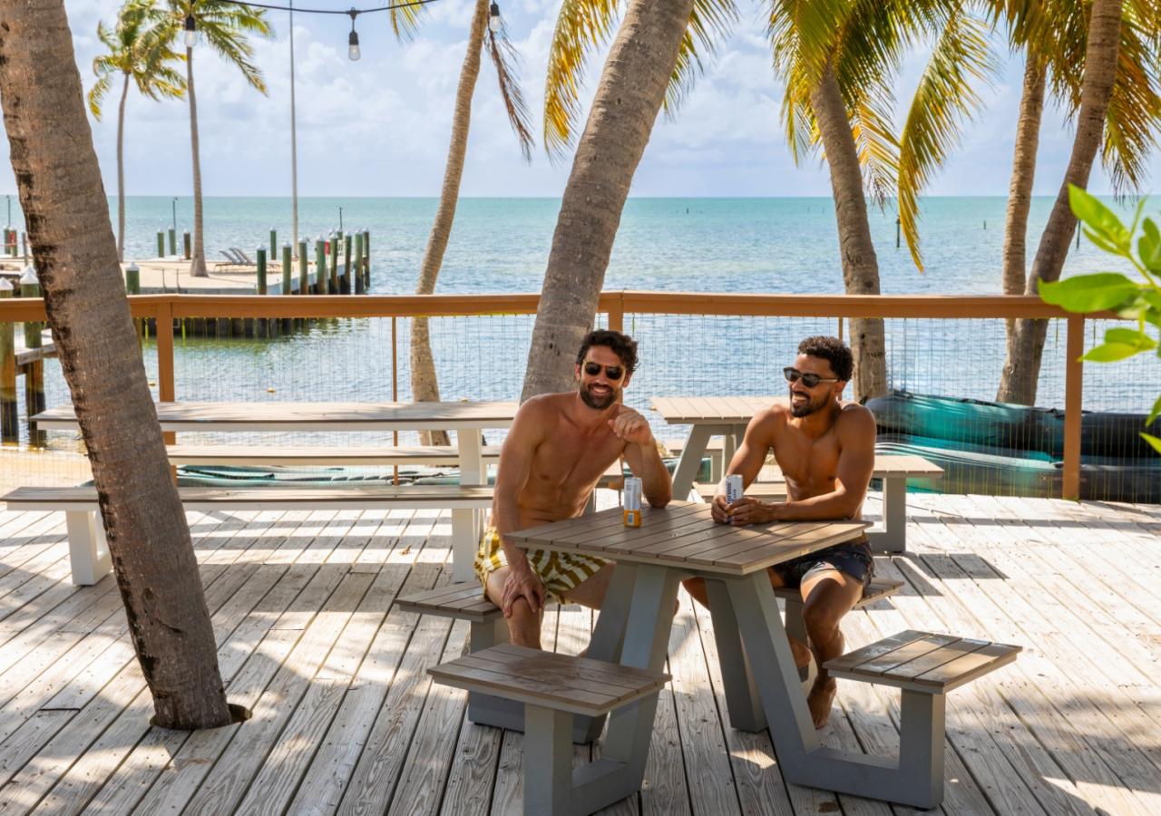 Two men sitting at a table with the ocean behind them at La Siesta Resort & Villas in Islamorada, FL.