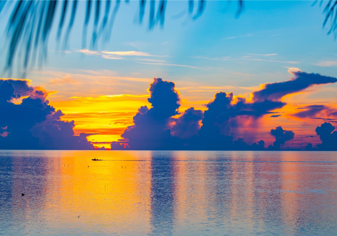 boat sailing across the ocean at sunset
