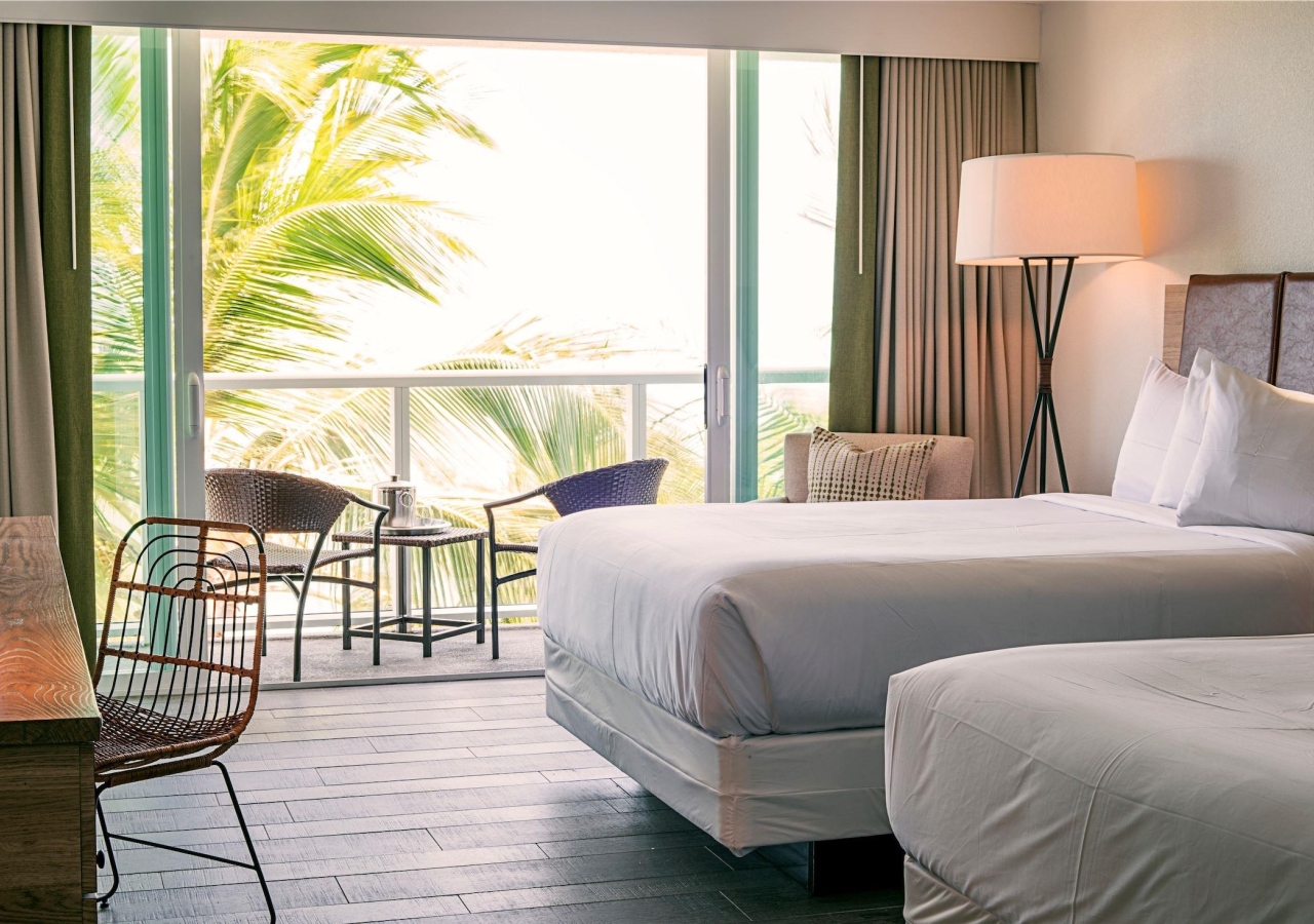bedroom with two queen beds and open balcony doors