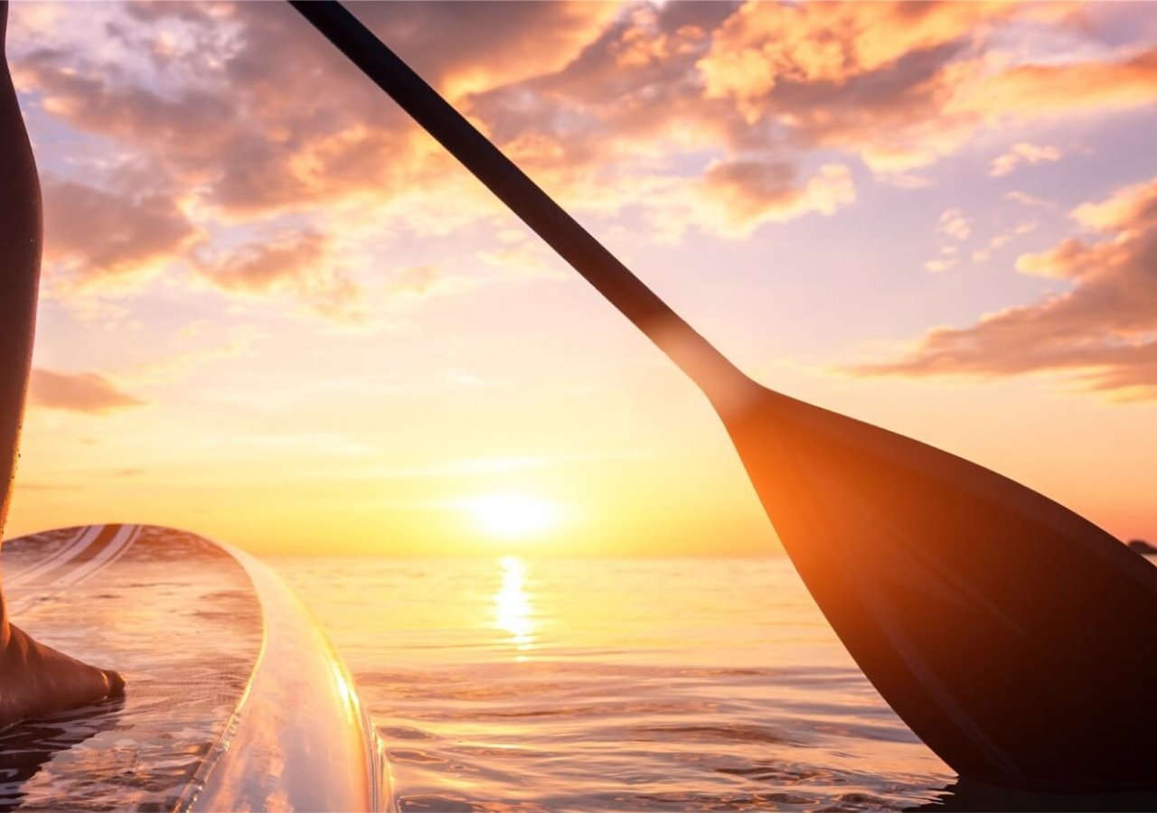 someone paddleboarding at sunset