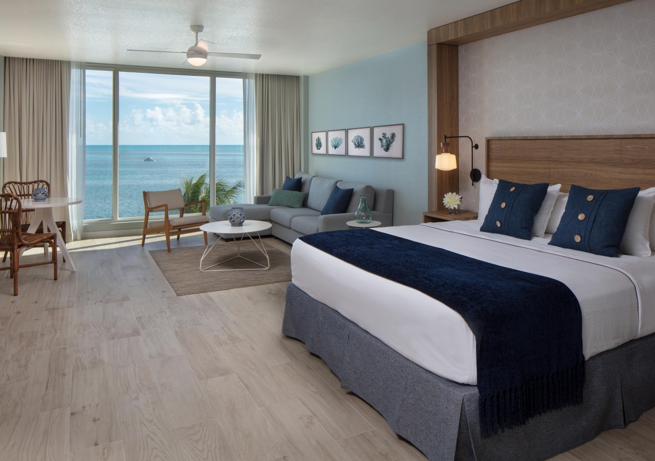 Room with a freshly made bed, and the ocean can be seen in the background out the window