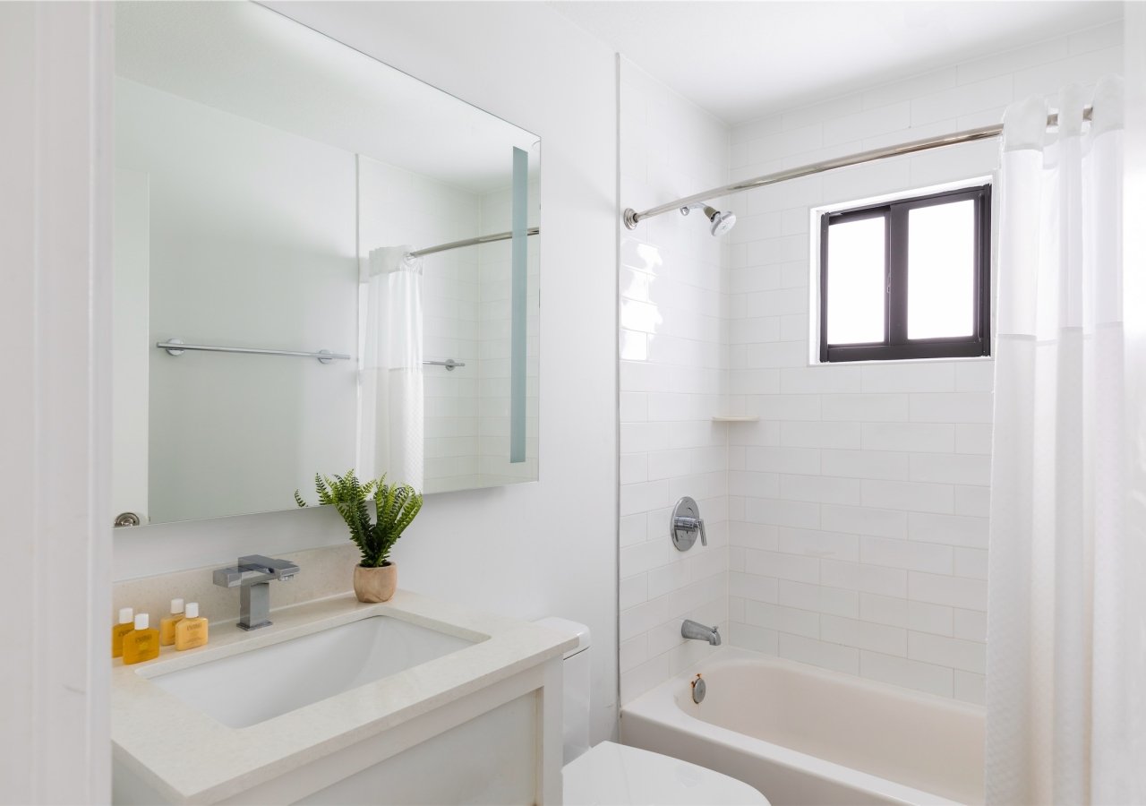 bathroom with small vanity and window in shower
