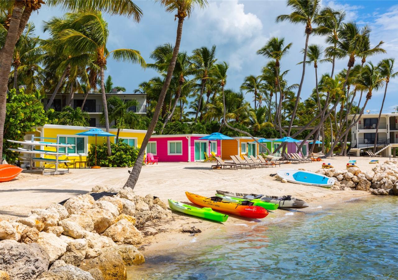 canoes on shore by the colorful cottages on the beach