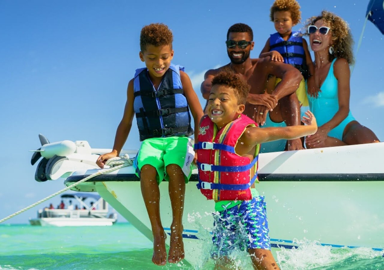 family jumping off a boat into the ocean