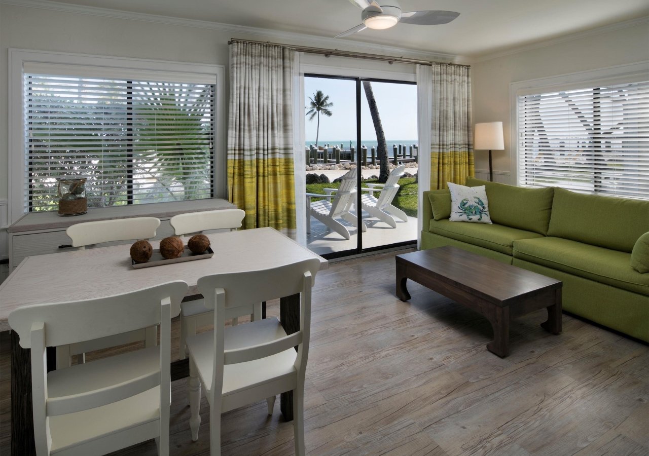 living room with green sofa and patio with view of ocean