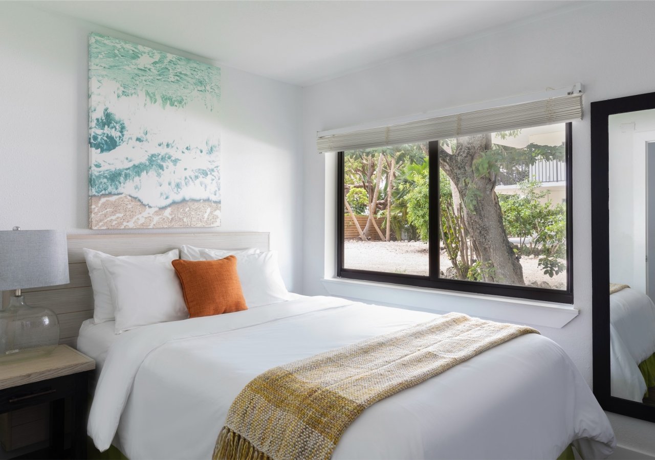 bedroom with view of beach and ocean artwork on the wall