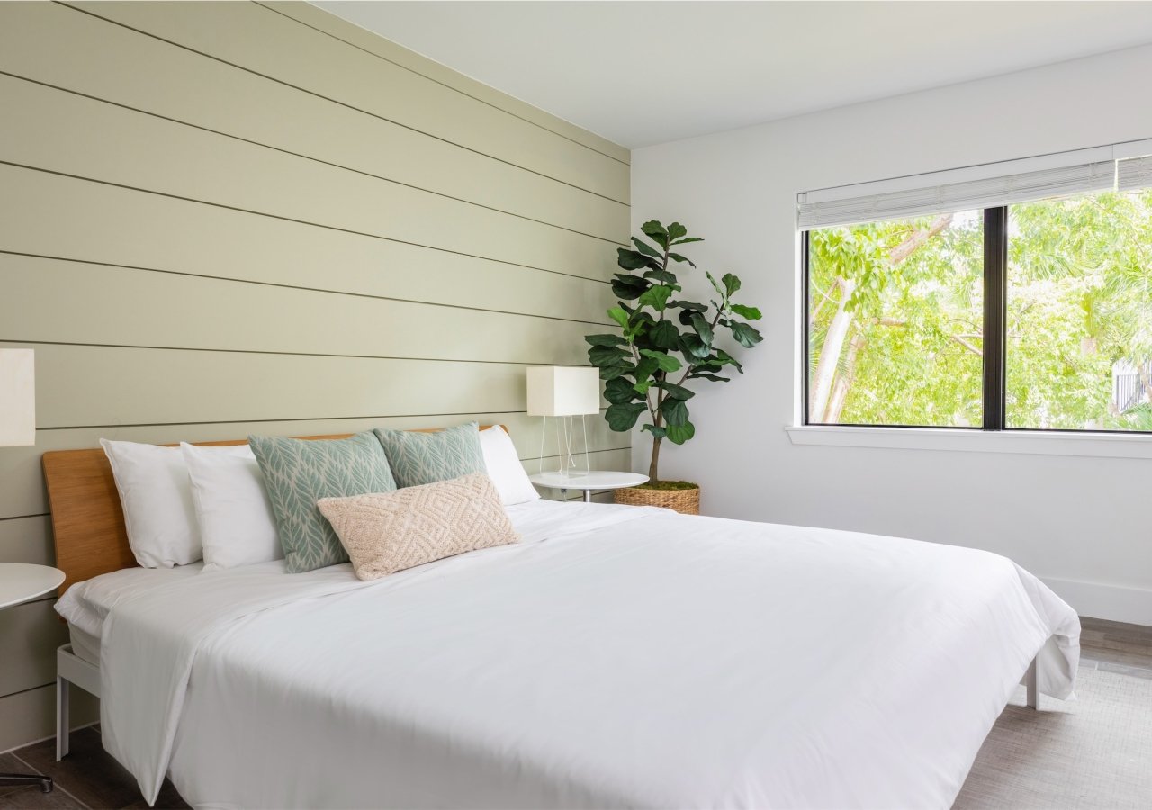 bedroom with green panelled wood wall and one kind bed