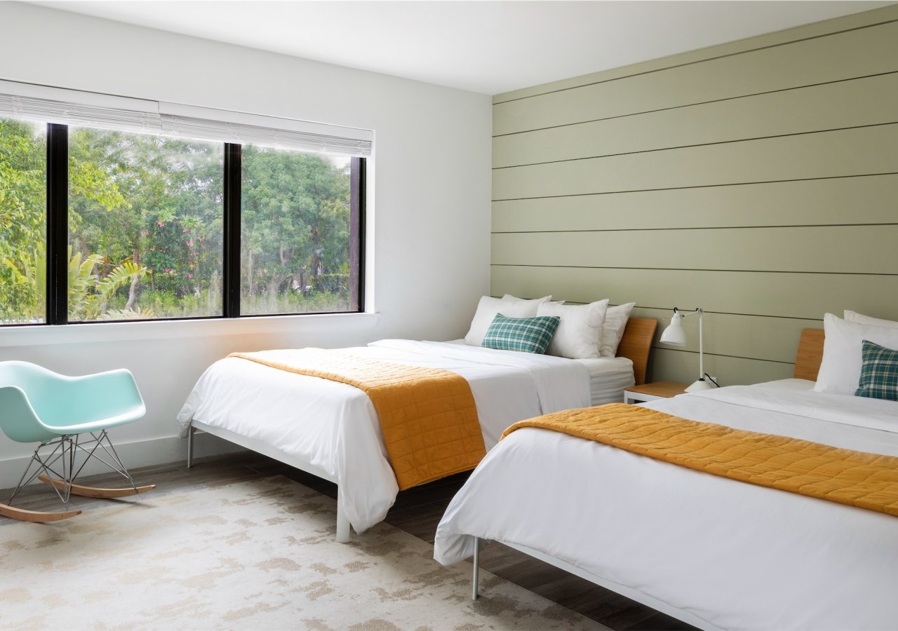 bedroom with green panelled wood wall and two queen beds