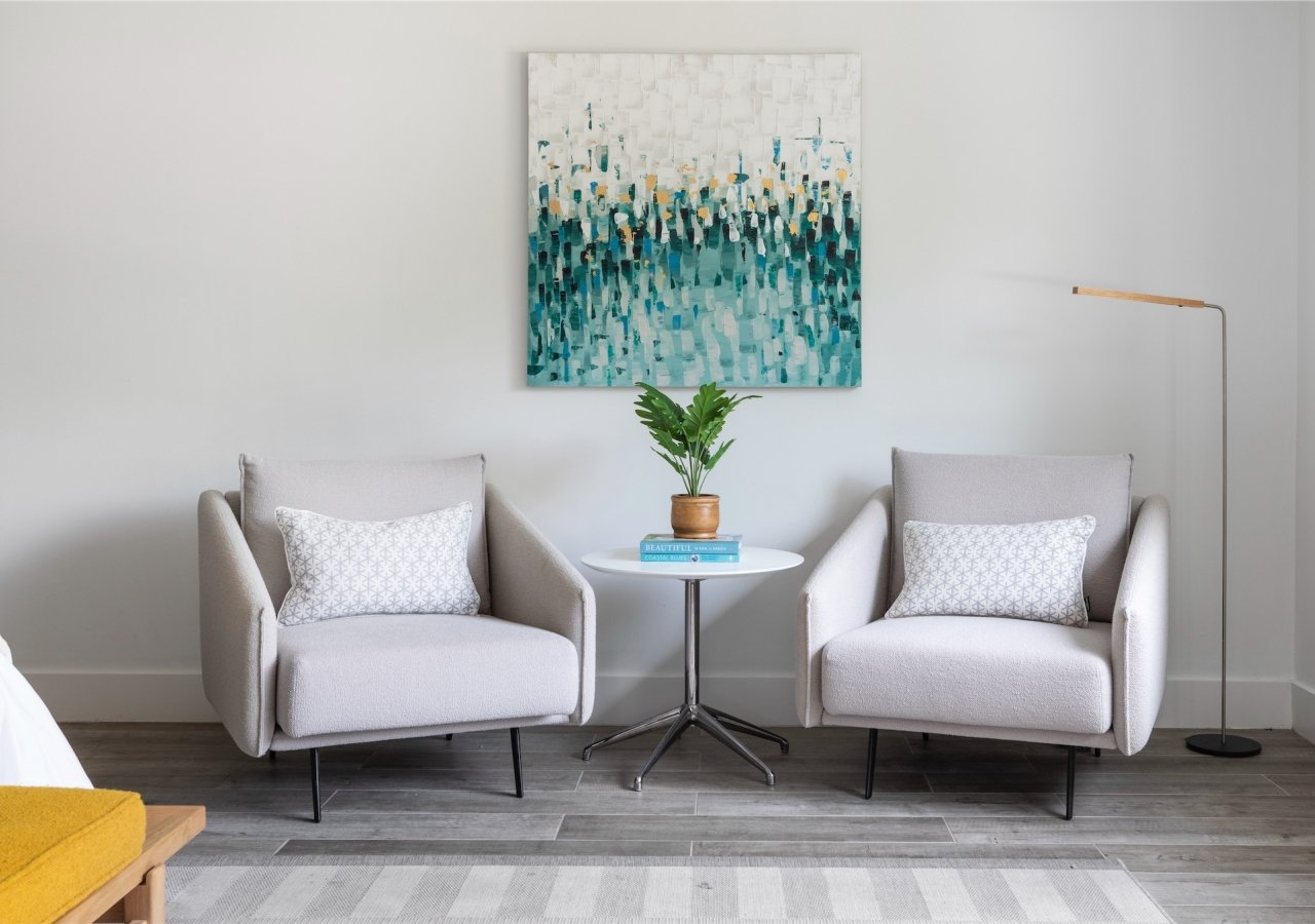 seating area with two chairs and a painting hanging above