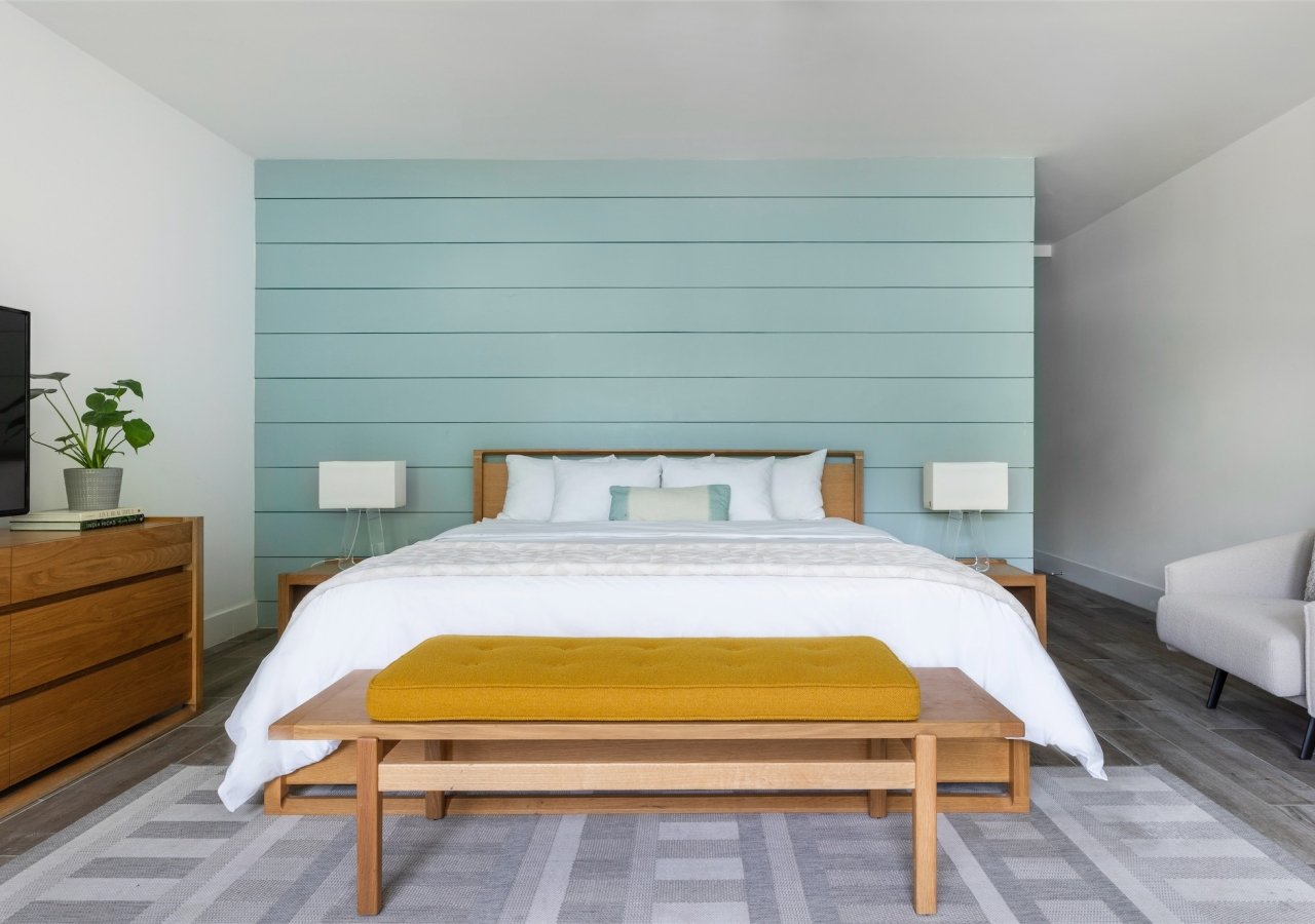 bedroom with king bed and sea blue wood paneled wall
