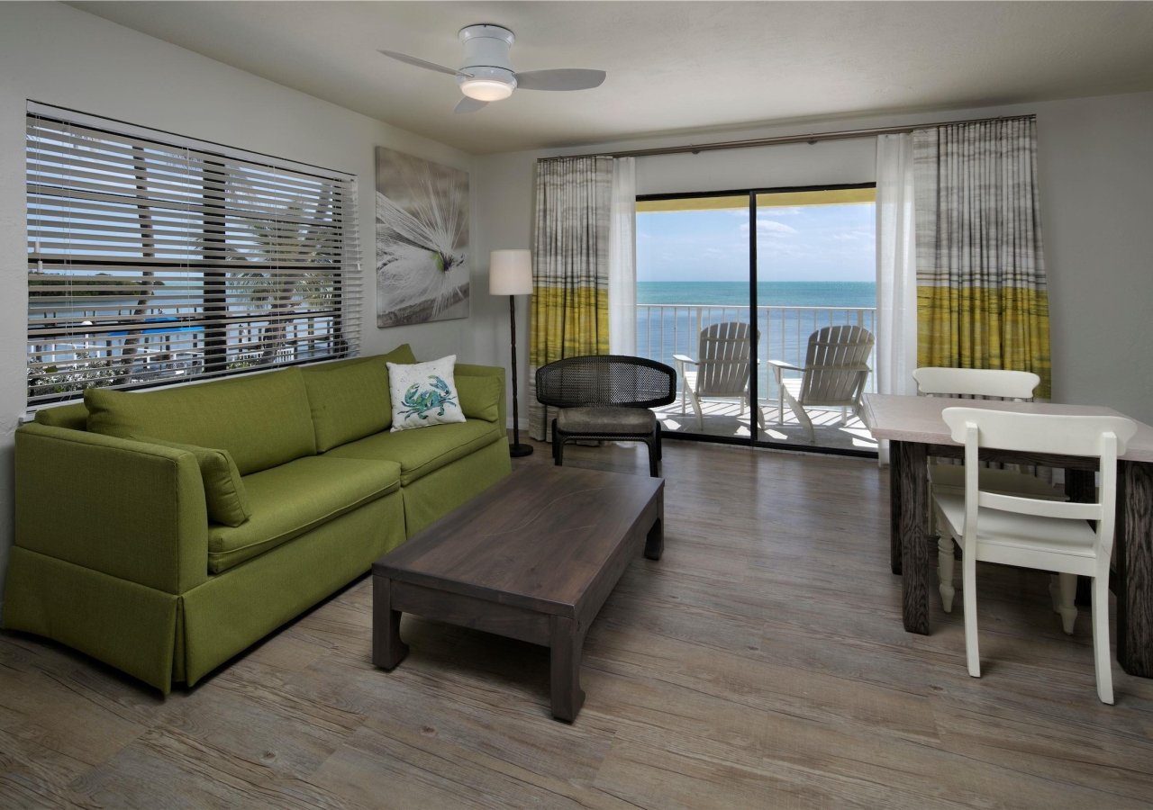 living room with green sofa and balcony overlooping the ocean