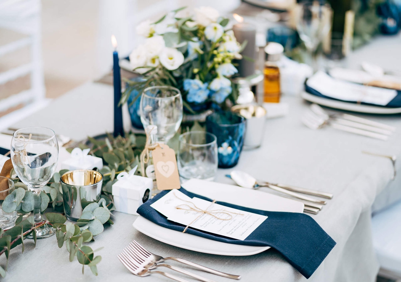long table set up for a formal dinner, on the beach