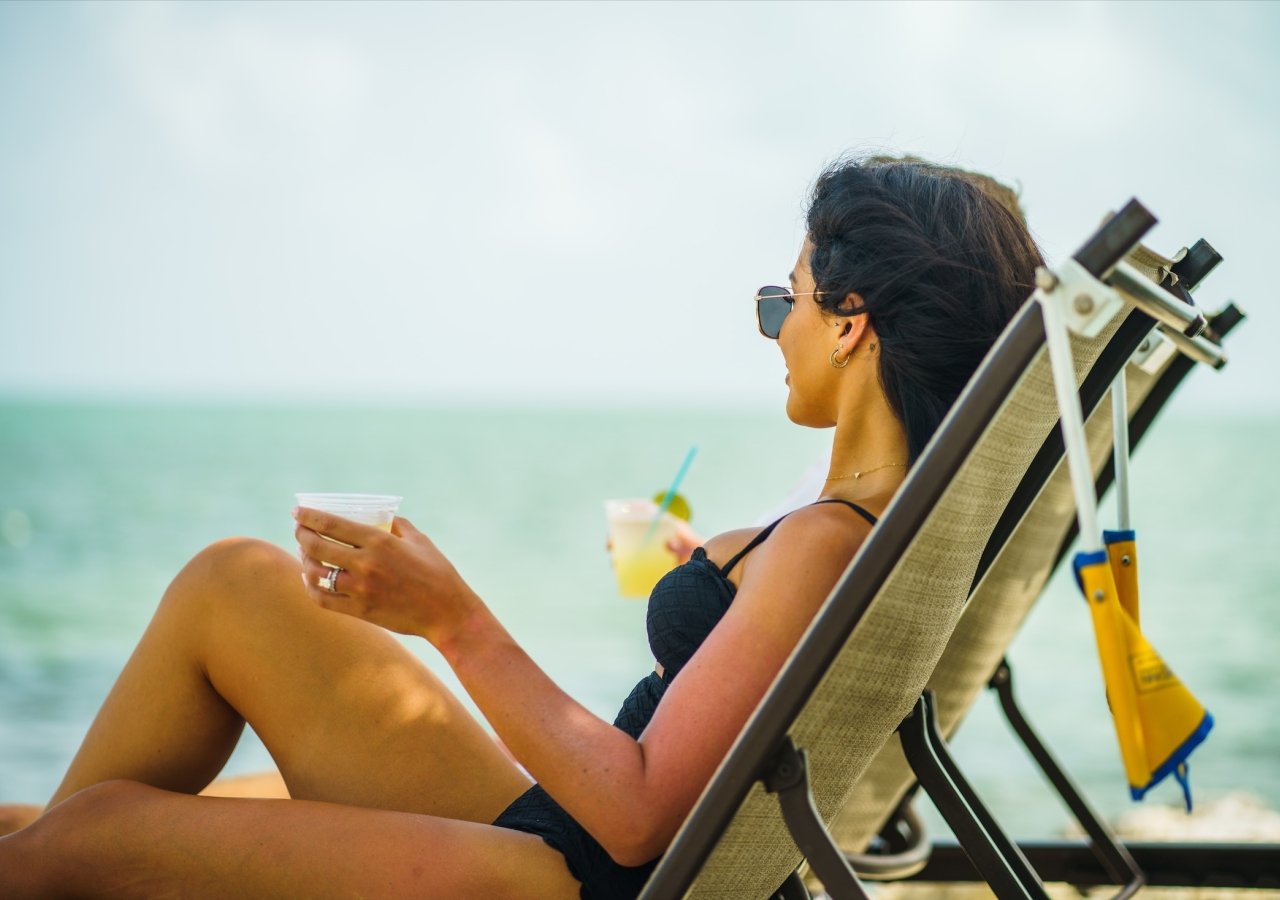 woman on the beach drinking a cocktail