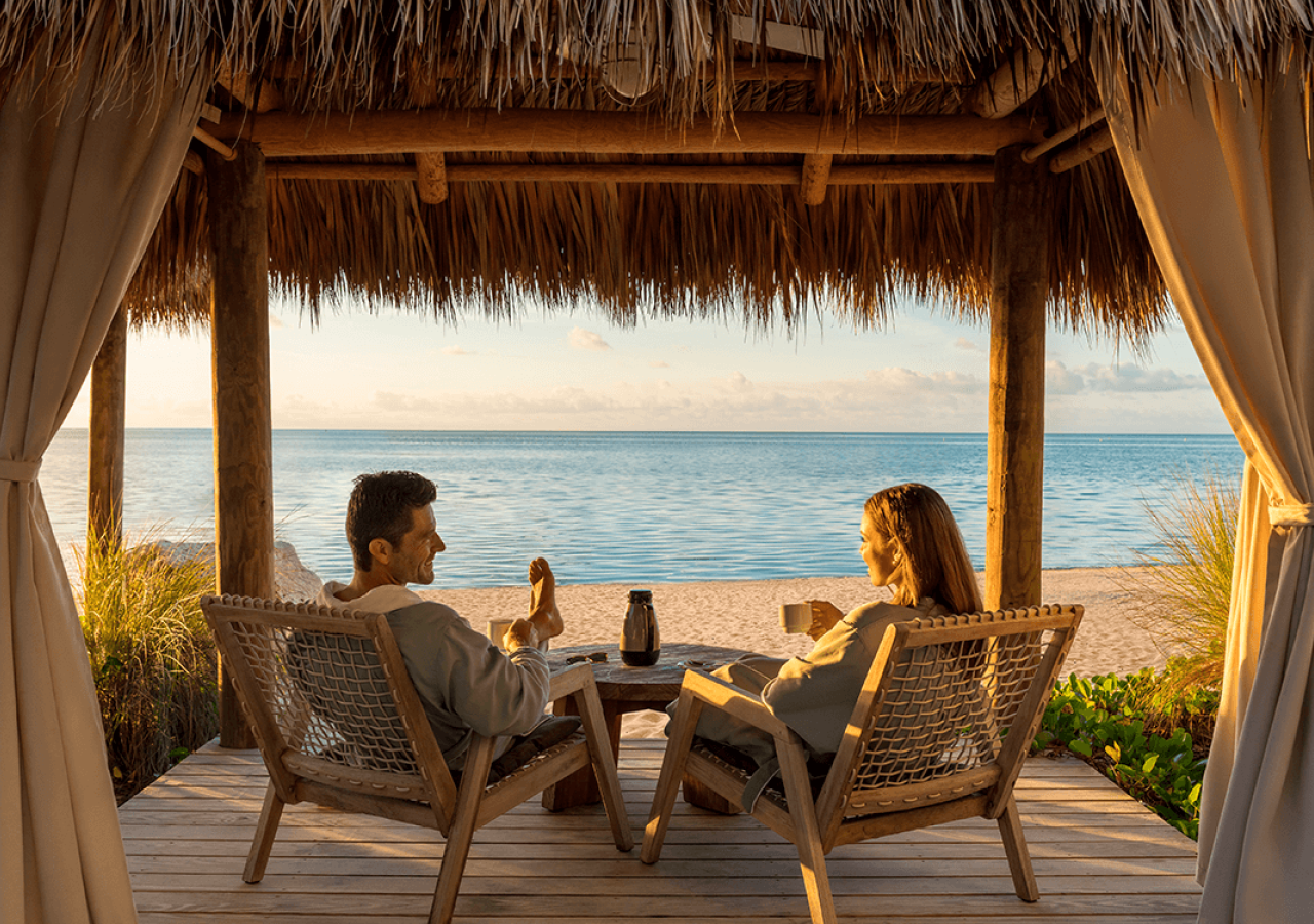 couple sitting under a hut on the ocean