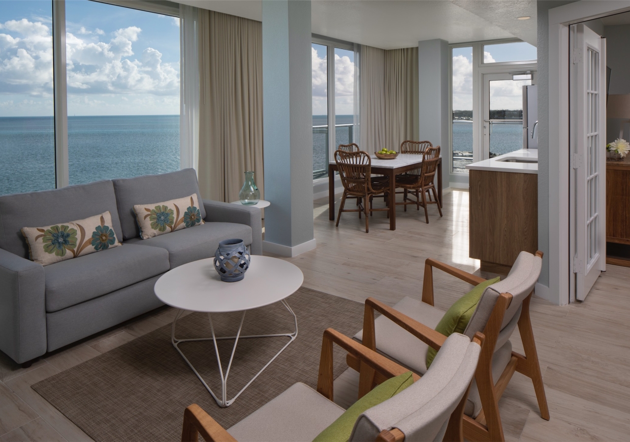 Living room with sofa and chairs and large picture windows with view of ocean
