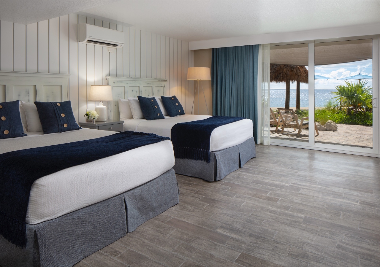 bedroom with two beds and lanai with lounge chairs overlooking the ocean