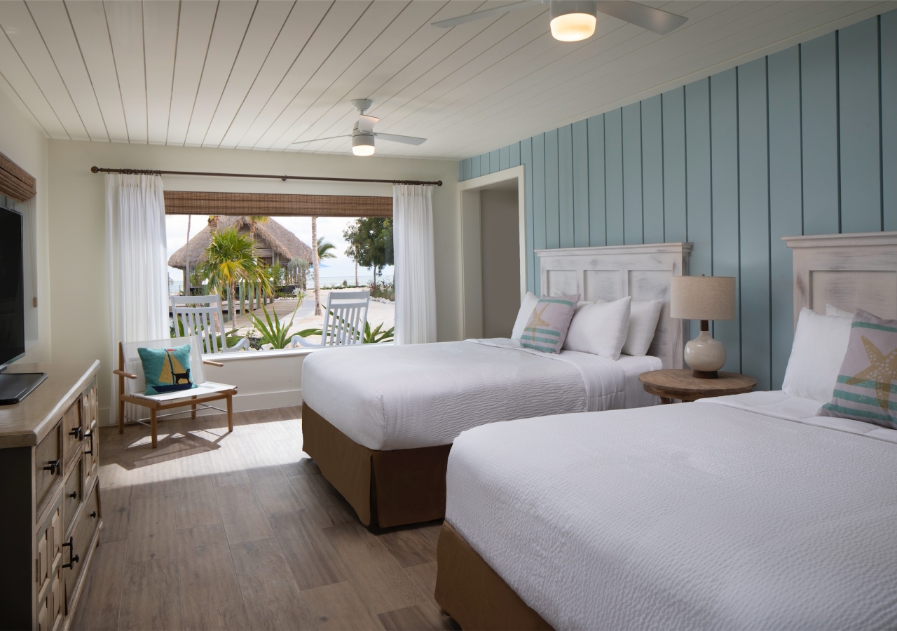 bedroom with two queen beds and pale blue wood panelled accent wall