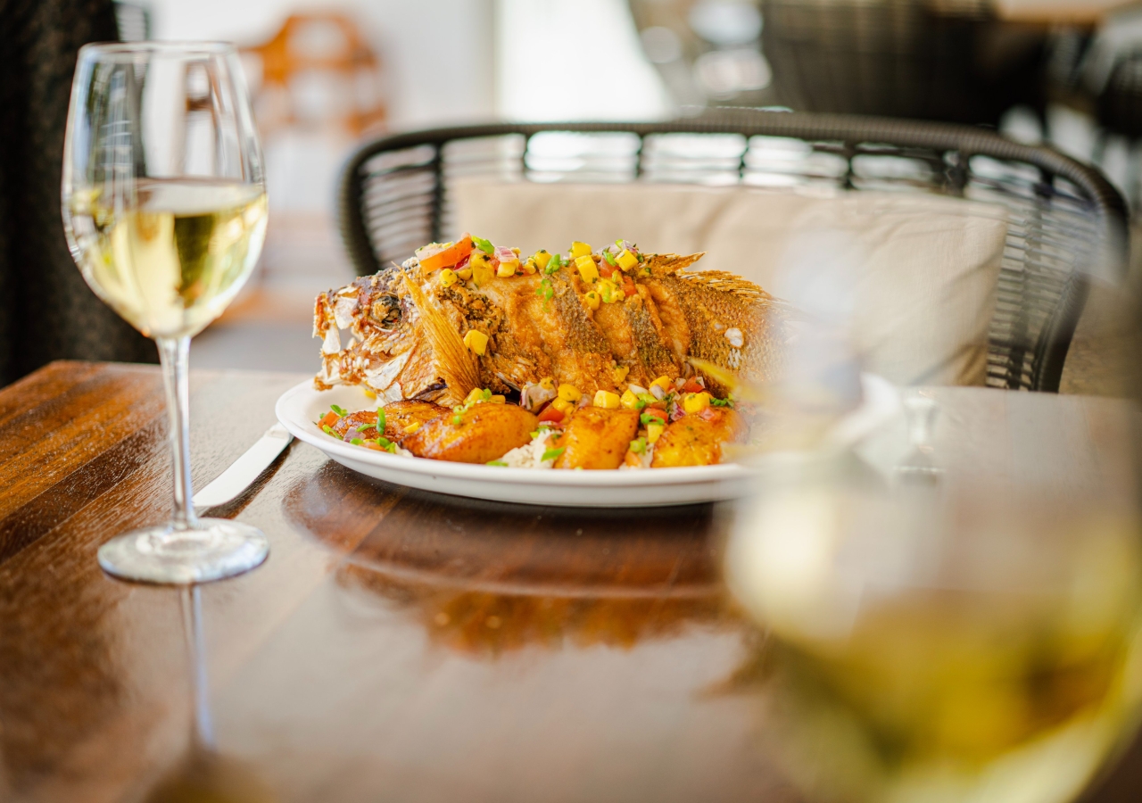 baked fish on a table with a glass of white wine