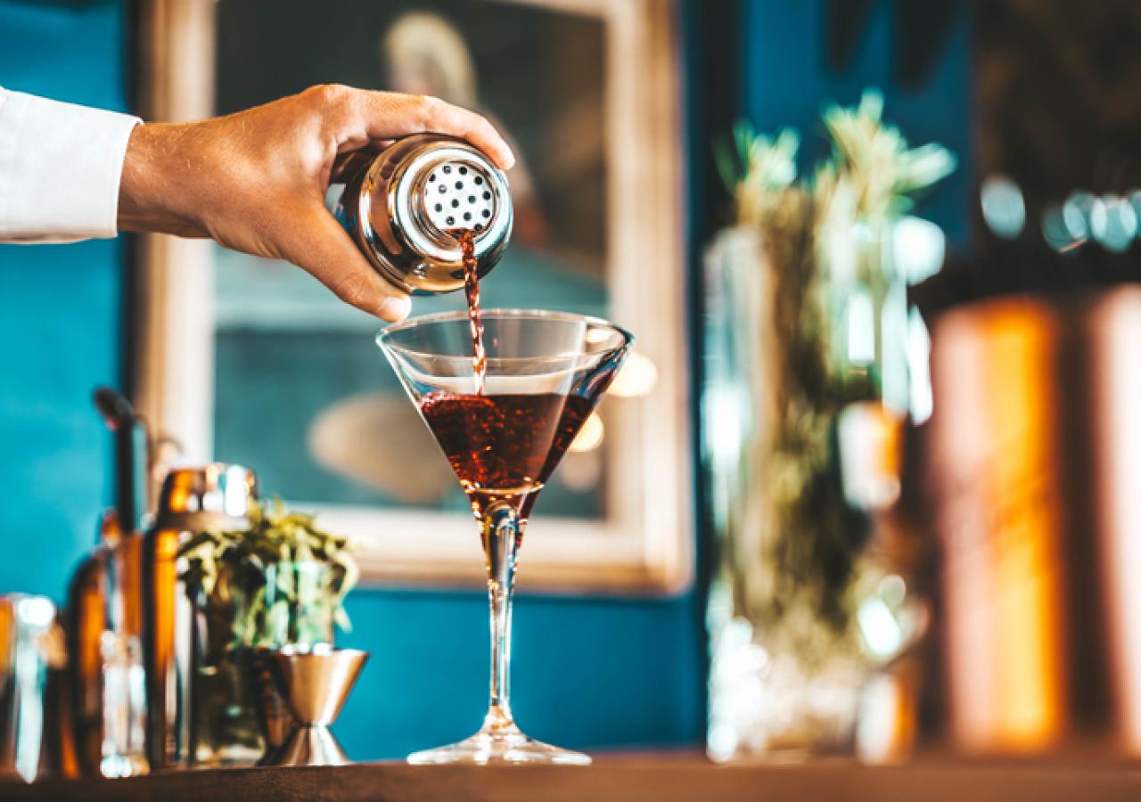 Bartender pouring drink into martini glass
