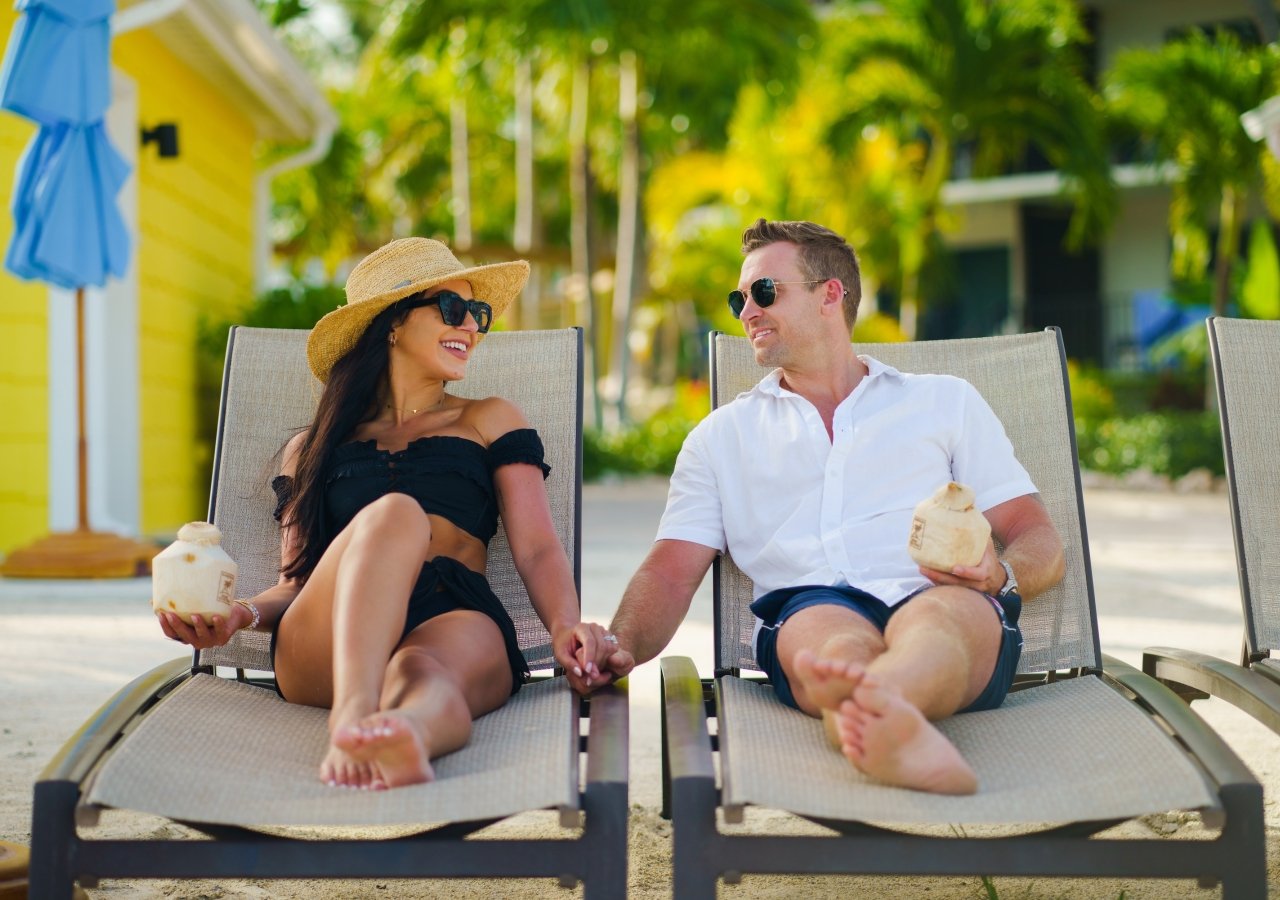 couple lounging chairs with drinks on the beach