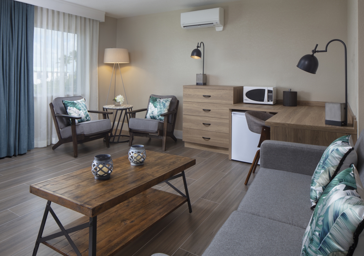 The living room area with coffee table, couch, chairs in the corner and a large window