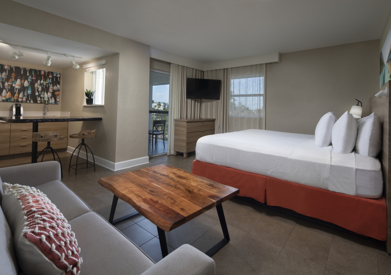 bed with a sofa area, and eating area visible in the background