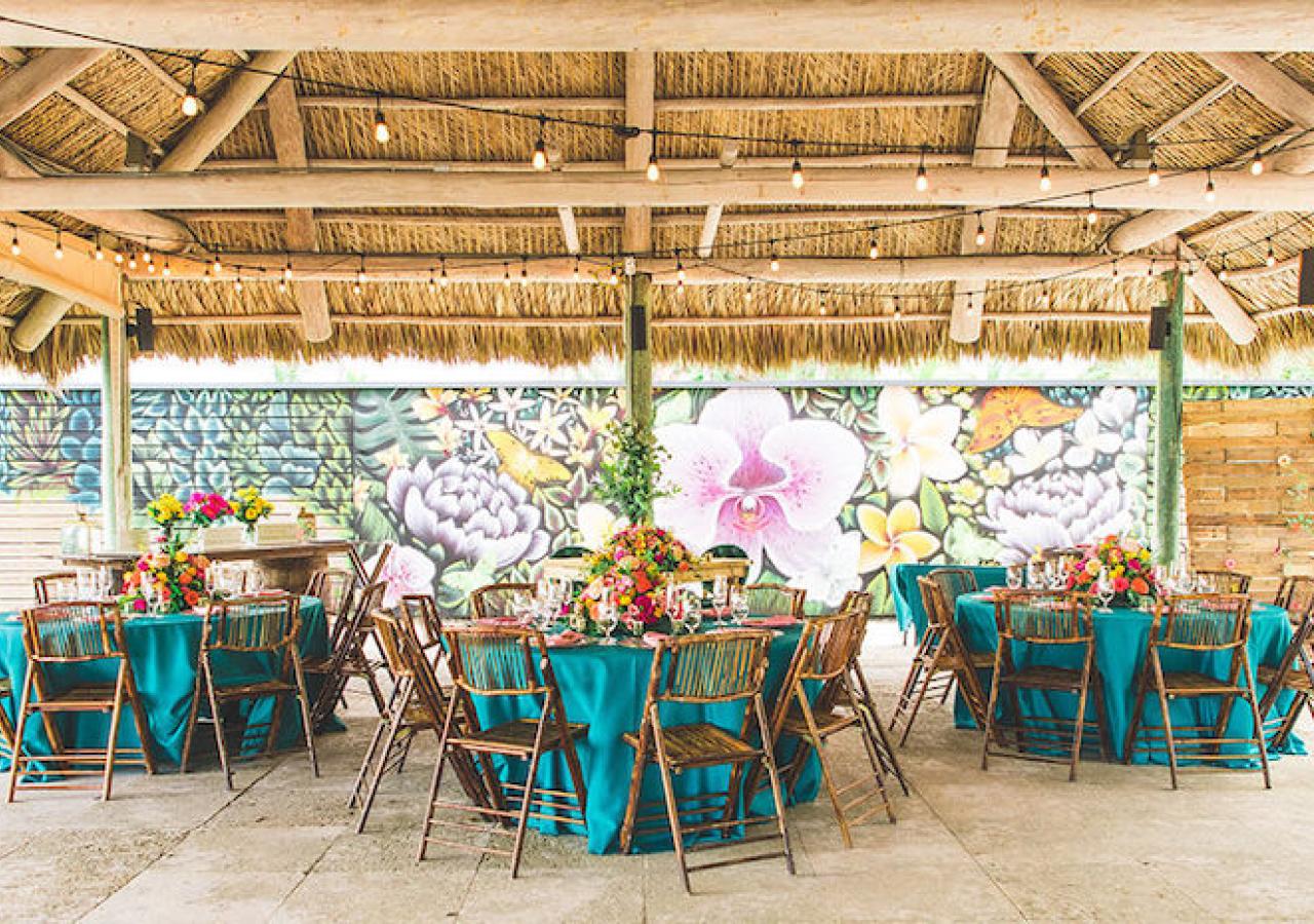 tiki with tables set up for a wedding, with colorful tablecloths 