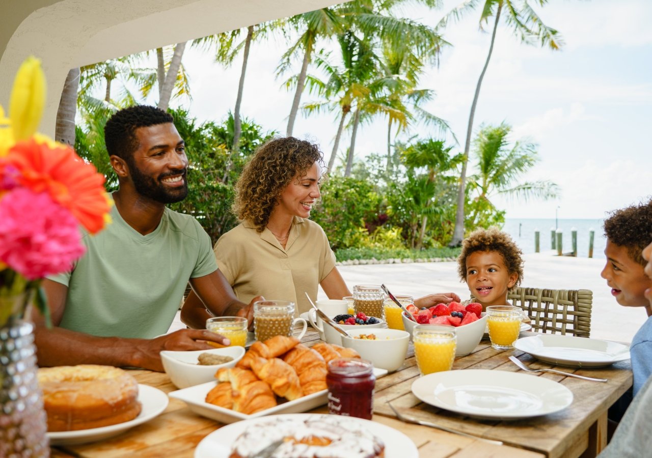 family having breakfast with the beach in the background