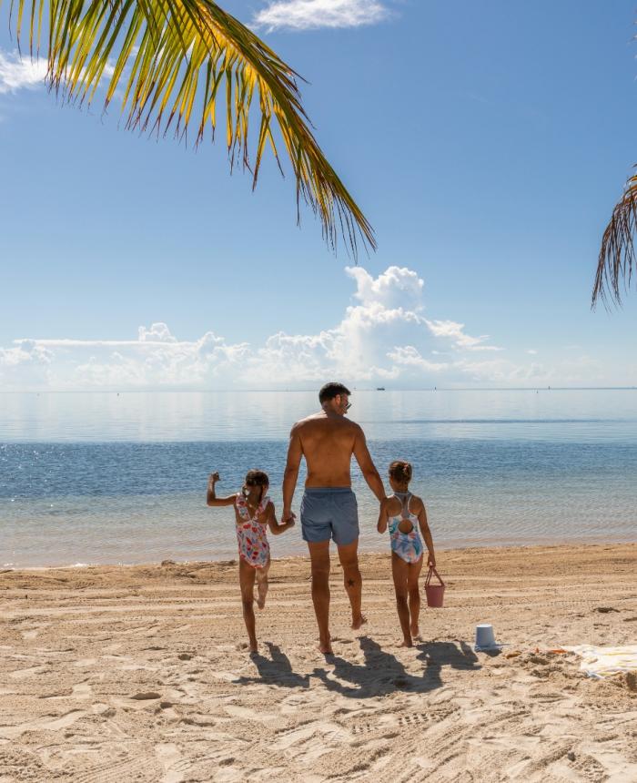 A dad walking to the ocean with his two girls at a beach at Three Waters Resort & Marina in Islamorada, Florida.