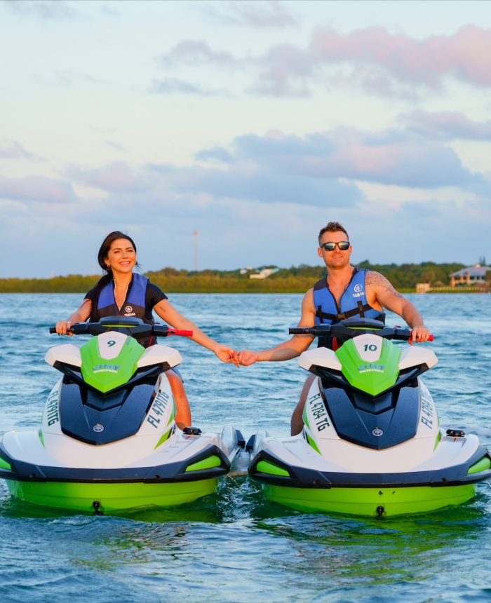 a couple holding hands while on separate jetskis