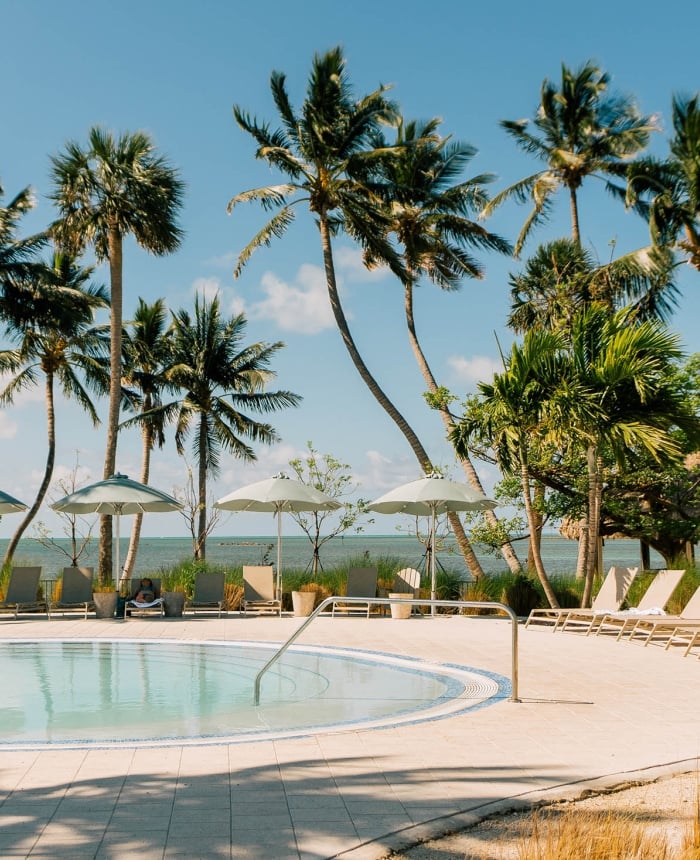 the pool deck at Amara Cay with the ocean and palm trees in the background