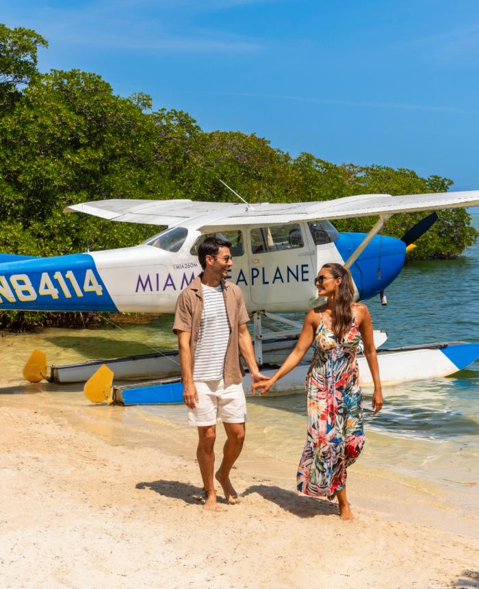 Two people on a beach with a plane in the background in the water