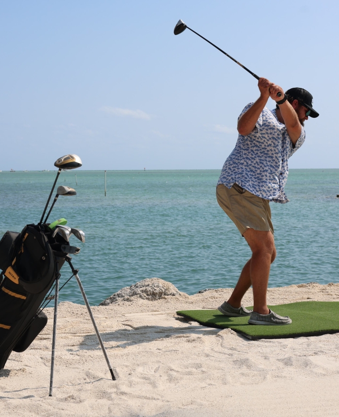 Man swinging a golf club on the beach