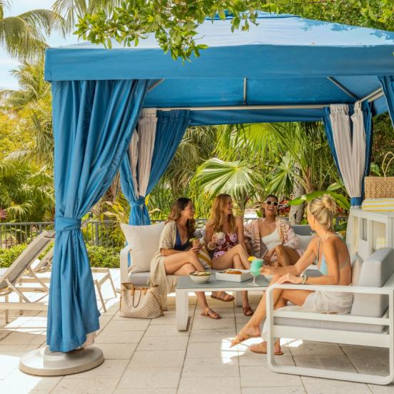 Friends sitting under a cabana at the pool at Three Waters Resort in Islamorada, Florida.