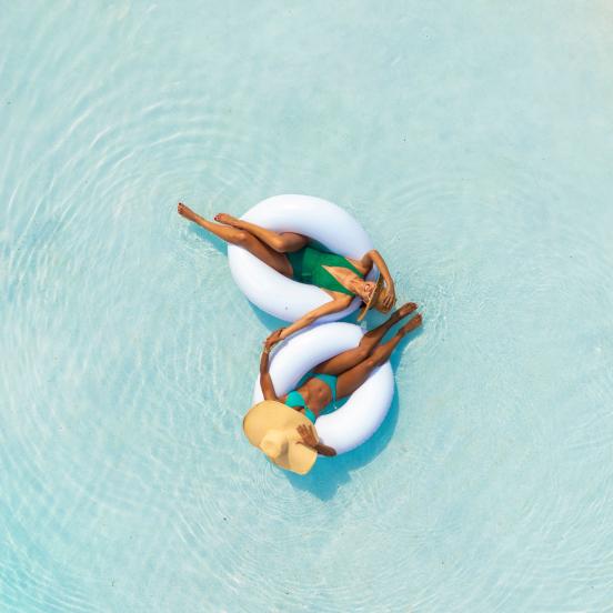 Two women floating in tubes in the pool