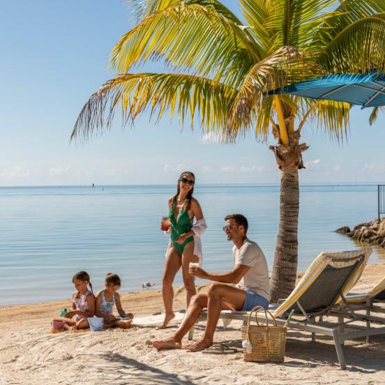 A family sitting at the beach at Three Waters Resort in Islamorada, Florida.