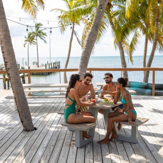 A group of people sitting outside enjoying drinks and food.