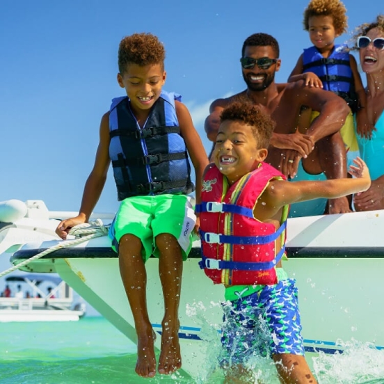 family jumping off a boat into the ocean