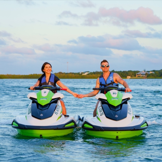 a couple holding hands while on separate jetskis