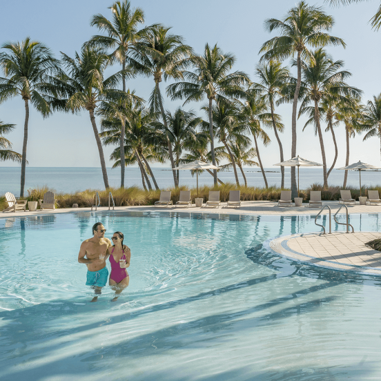 Couple walking in a pool with palmtrees in the background