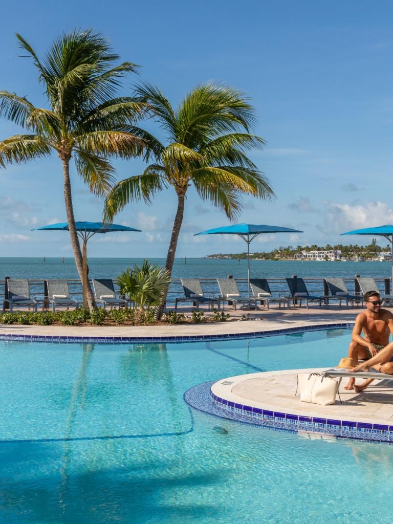 A couple sitting by the pool on chaise lounges.