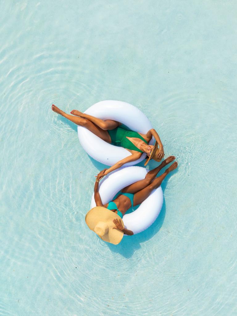 Two women floating in tubes in the pool