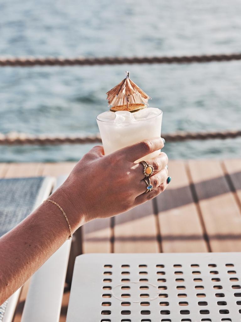 A woman holding a drink by the pool.