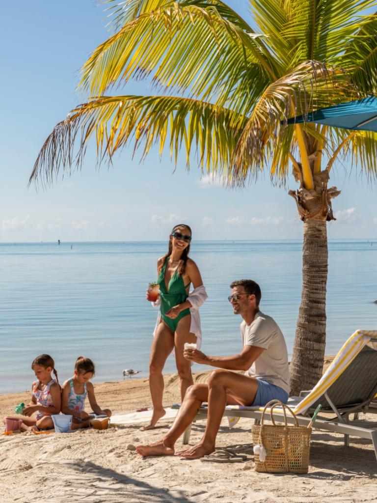 A family sitting at the beach at Three Waters Resort in Islamorada, Florida.