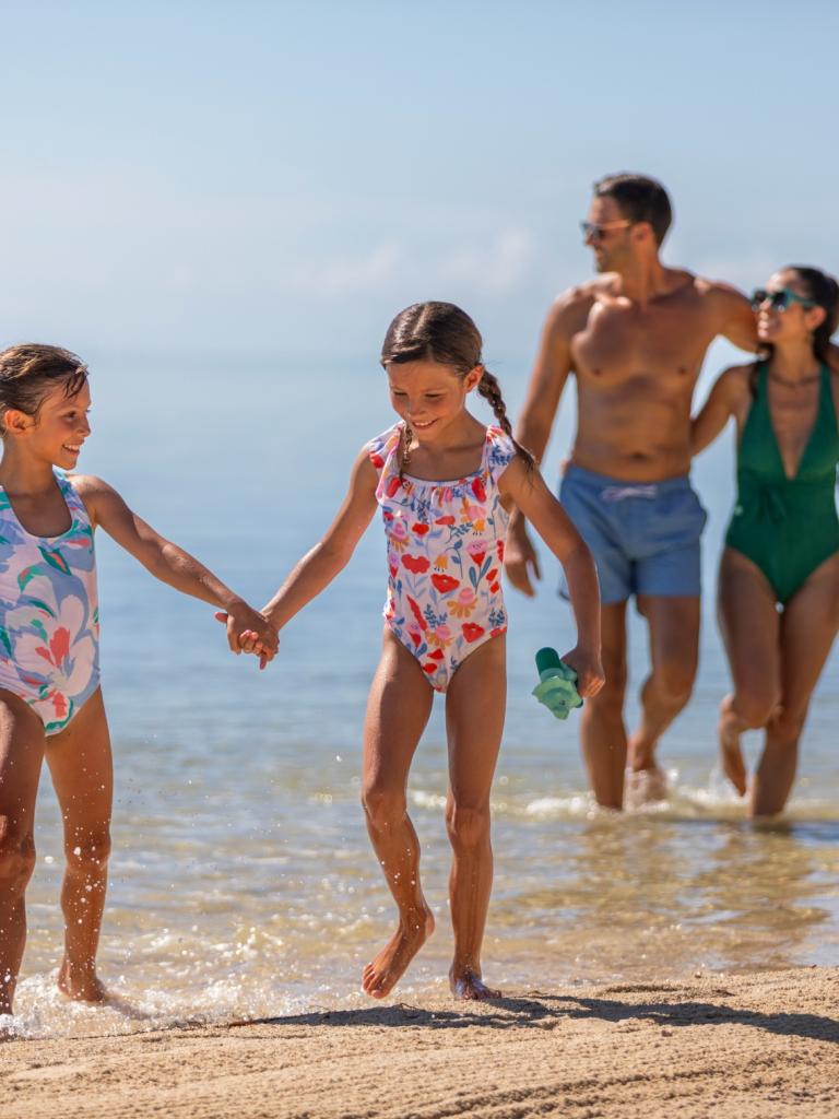 A family walking in the ocean at the beach.