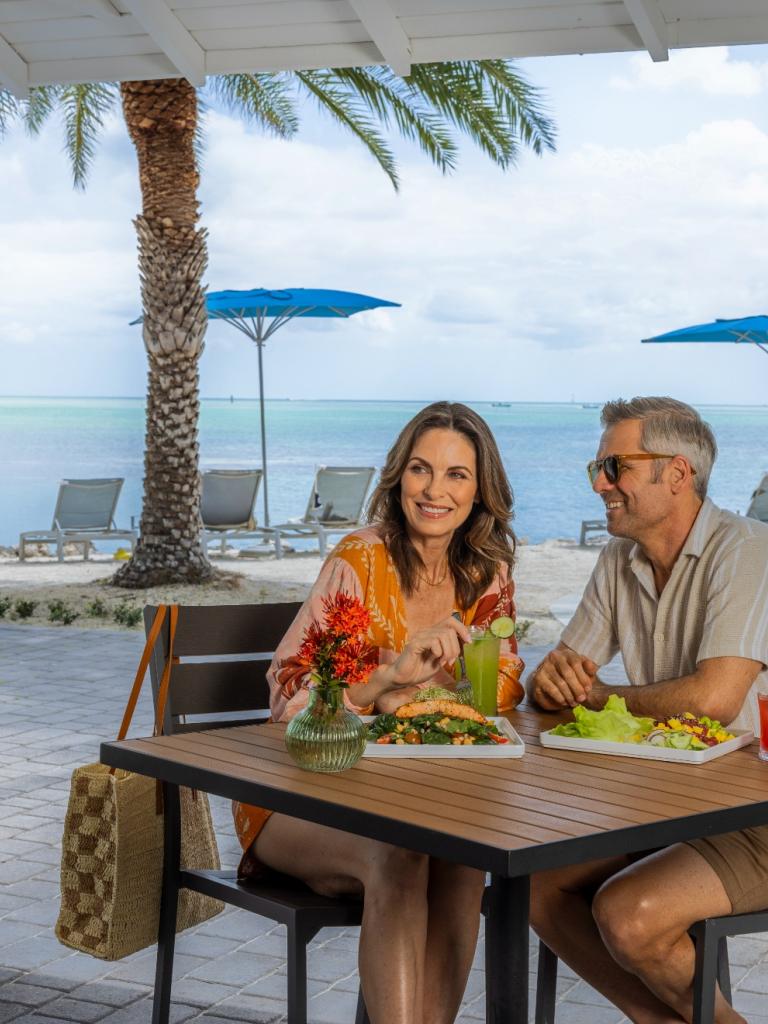 A couple sits at a table at Hideaway, a beachfront restaurant in Islamorada, Florida at Three Waters Resort & Marina.